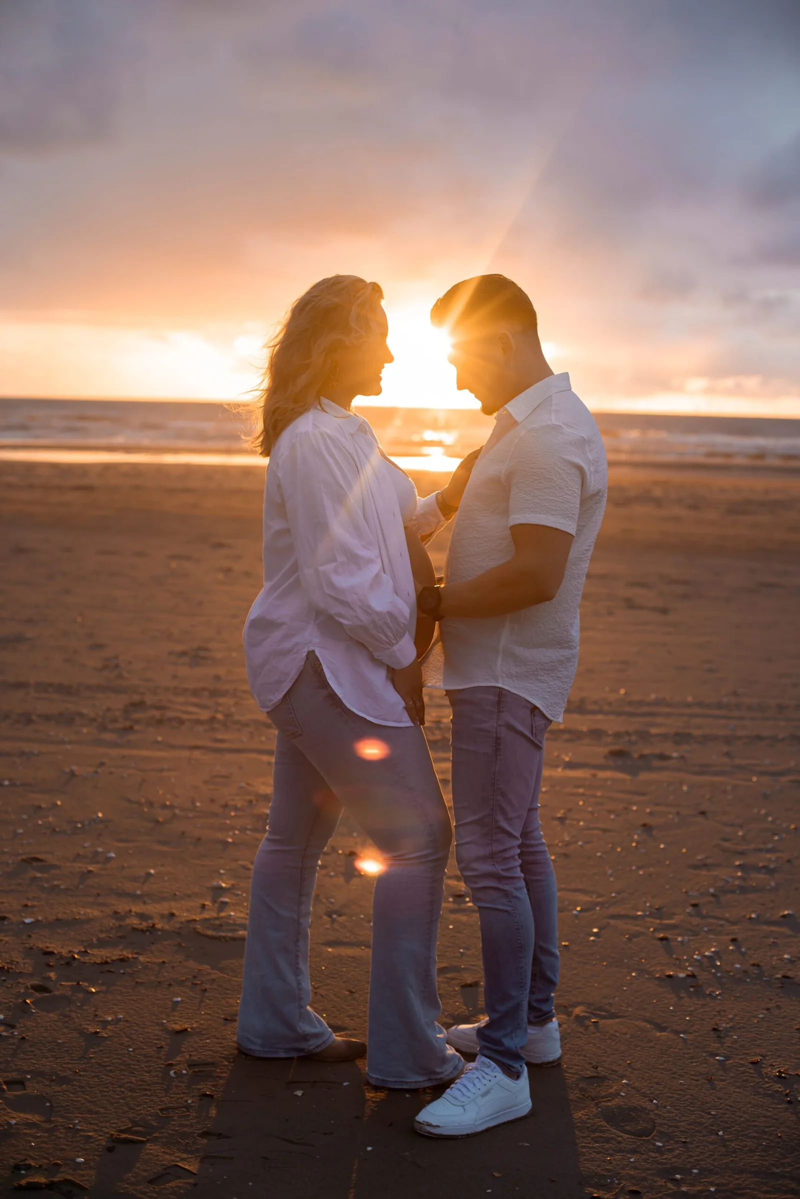 Zwanger stel op het strand tijdens zonsondergang